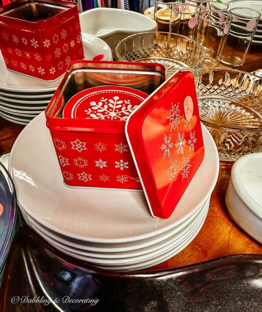 Vintage red tin can filled with red and white snowflake paper coasters in thrift store for apres ski decor.