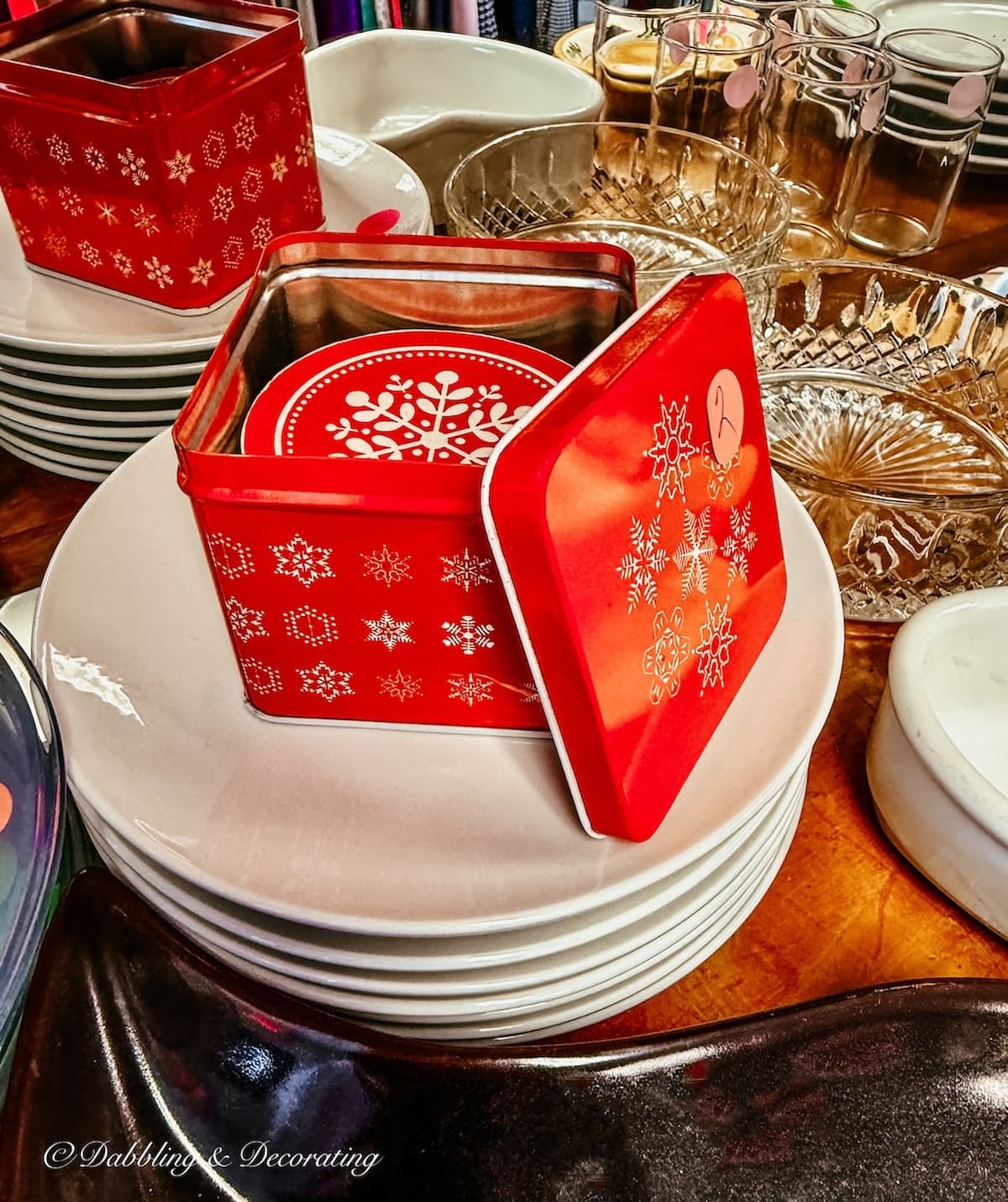 Vintage red tin can filled with red and white snowflake paper coasters in thrift store for apres ski decor.