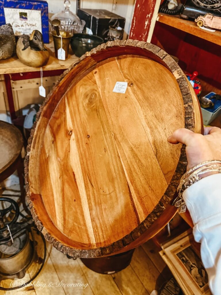 Vintage wooden round tray in hand at antique store for apres ski decor.