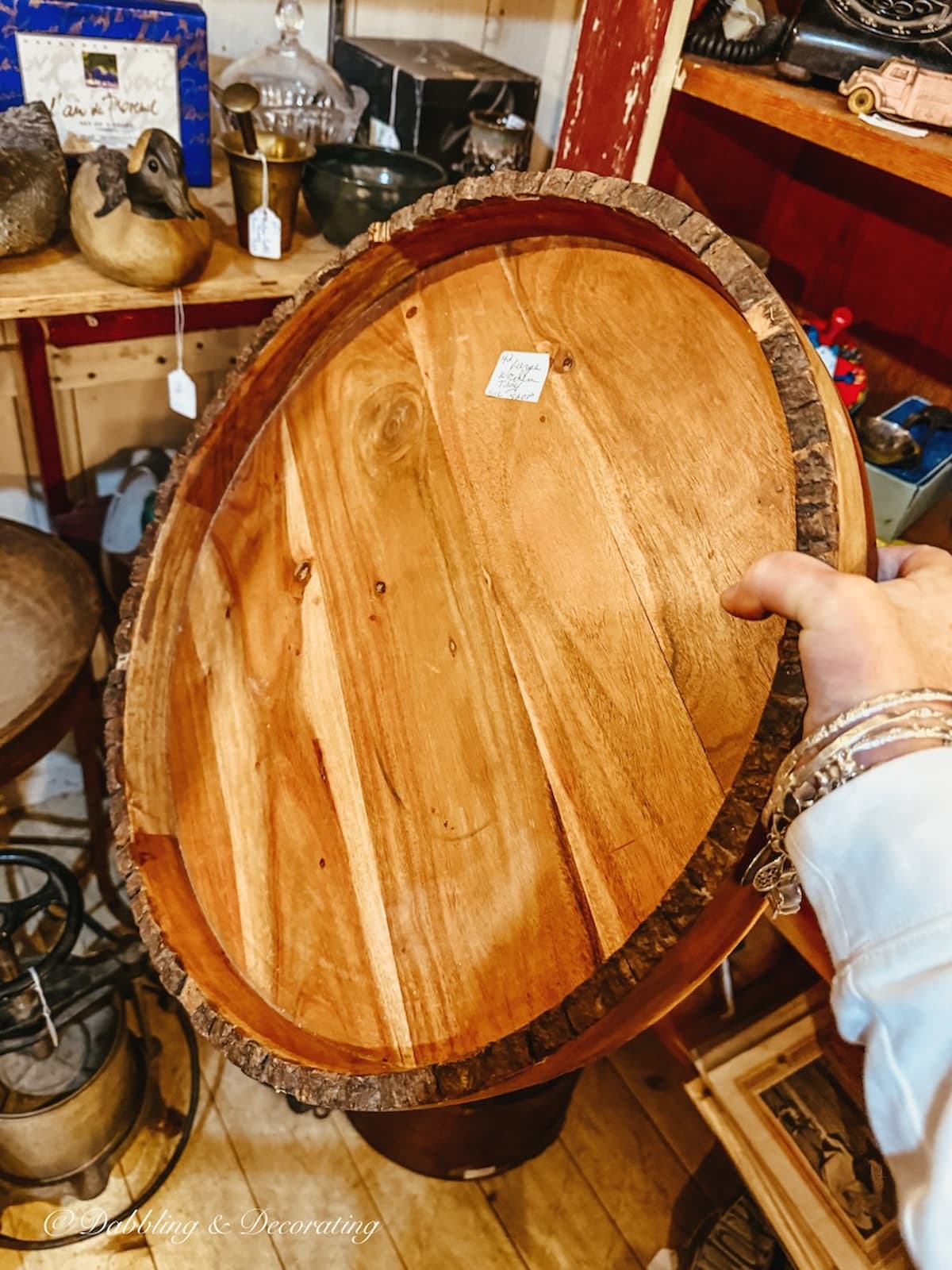 Vintage wooden round tray in hand at antique store for apres ski decor.