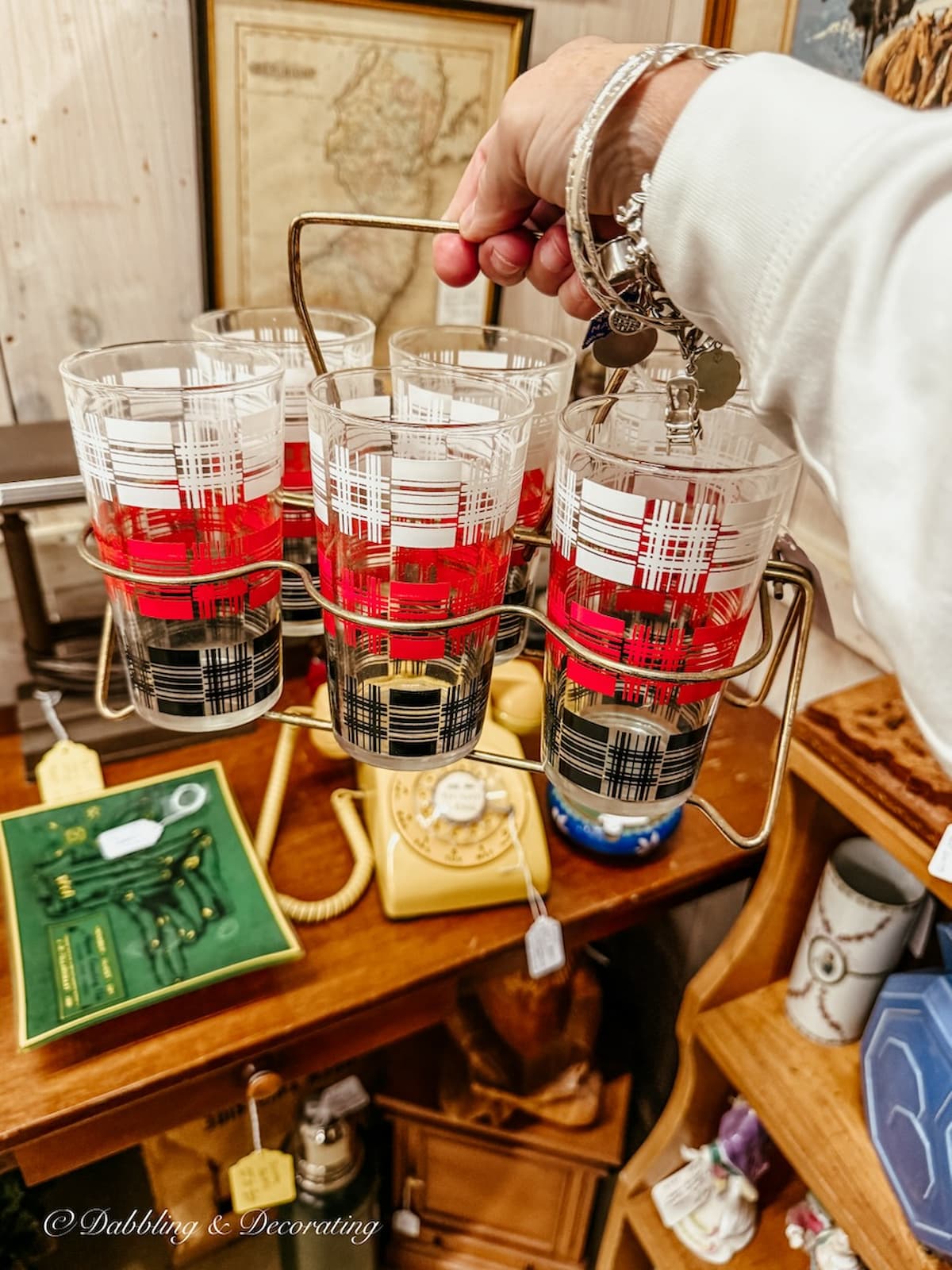 Rack of mid-century modern glassware in hand at antique store for apres ski decor ideas.