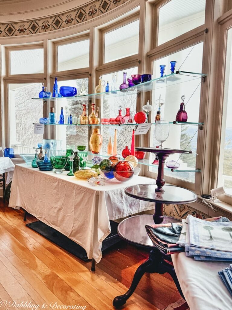 Dining room at luxury estate sale with dome windows and a table and shelving filled with colored glassware in how to shop estate sales at high end homes.