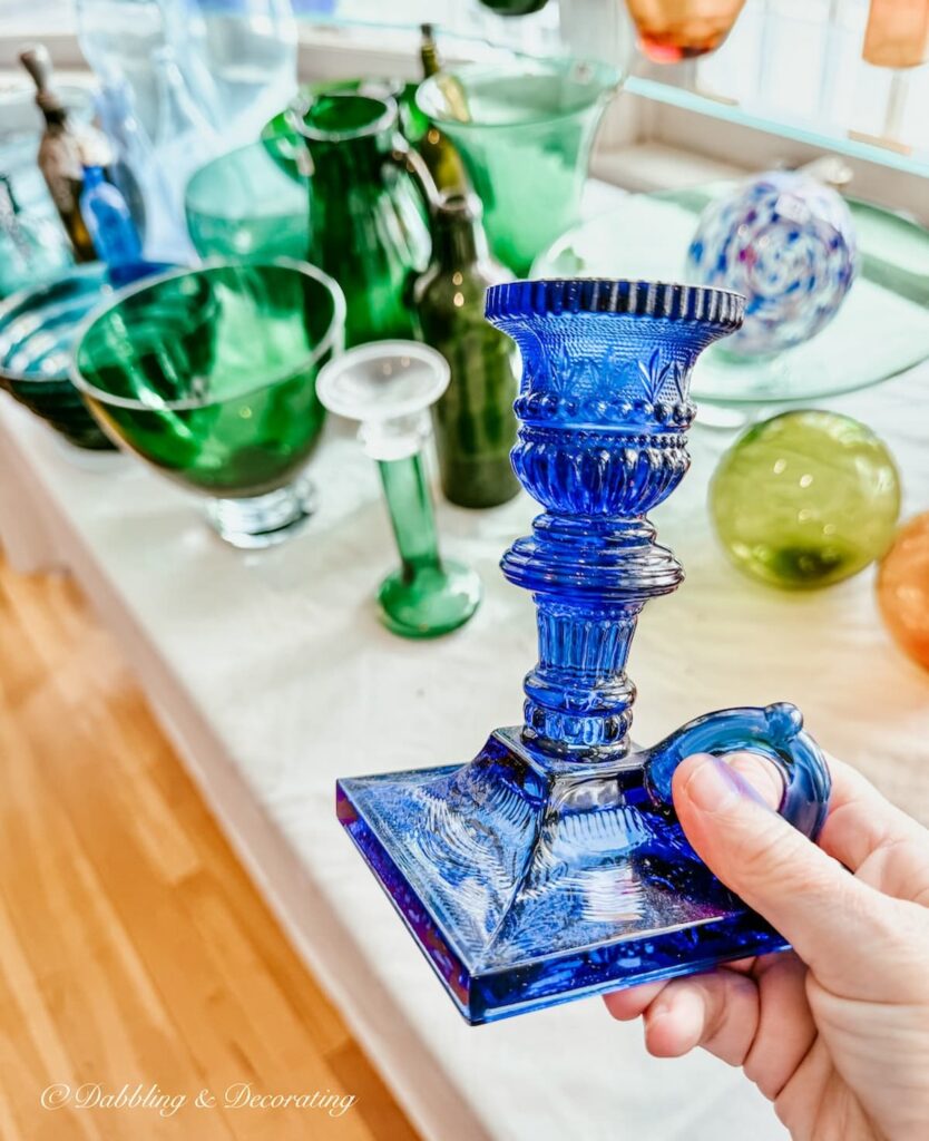 Blue glass candlestick in hand in learning how to shop estate sales in luxury homes.