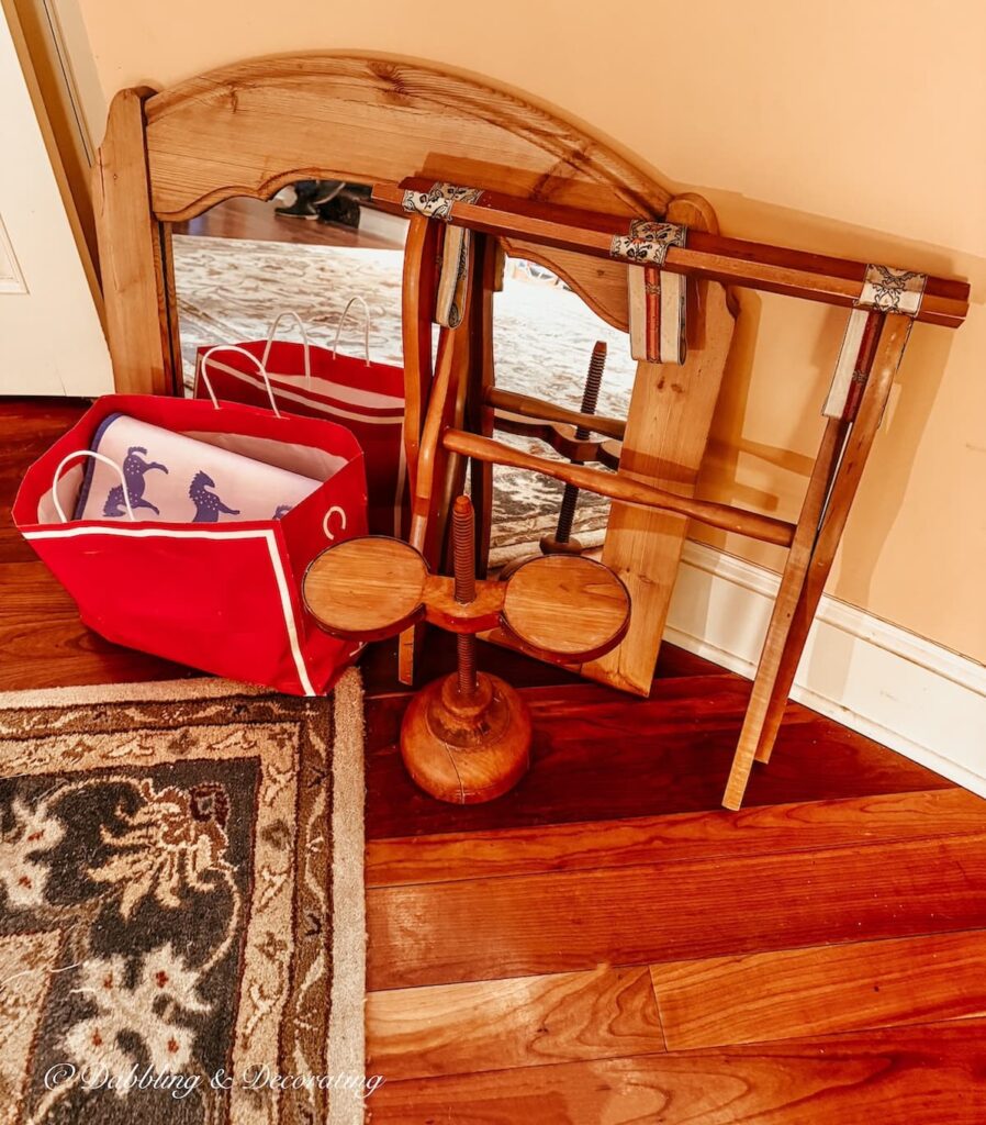 Vintage haul of antique mirror, luggage rack and red bag leaning on wall at how to shop an estate sale post.