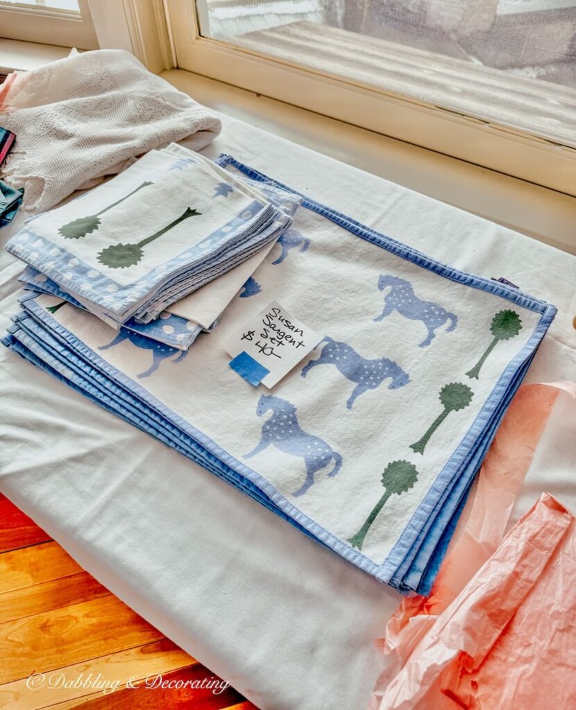 A set of Susan Sargent placemats and napkins at a luxury estate sale in Vermont on table.