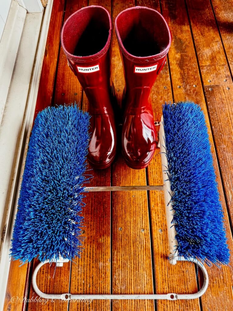 blue boot cleaner found at an estate sale in Vermont next to red Wellies boots on front porch.