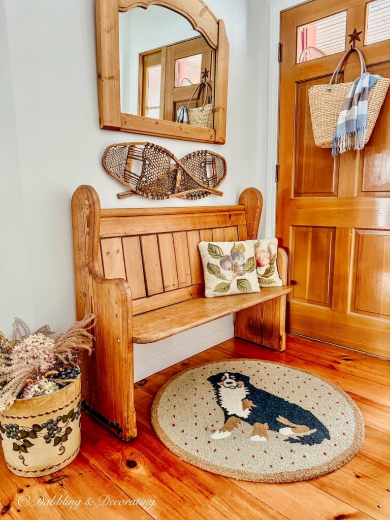 Vintage church pew entryway with embroidered pillows.