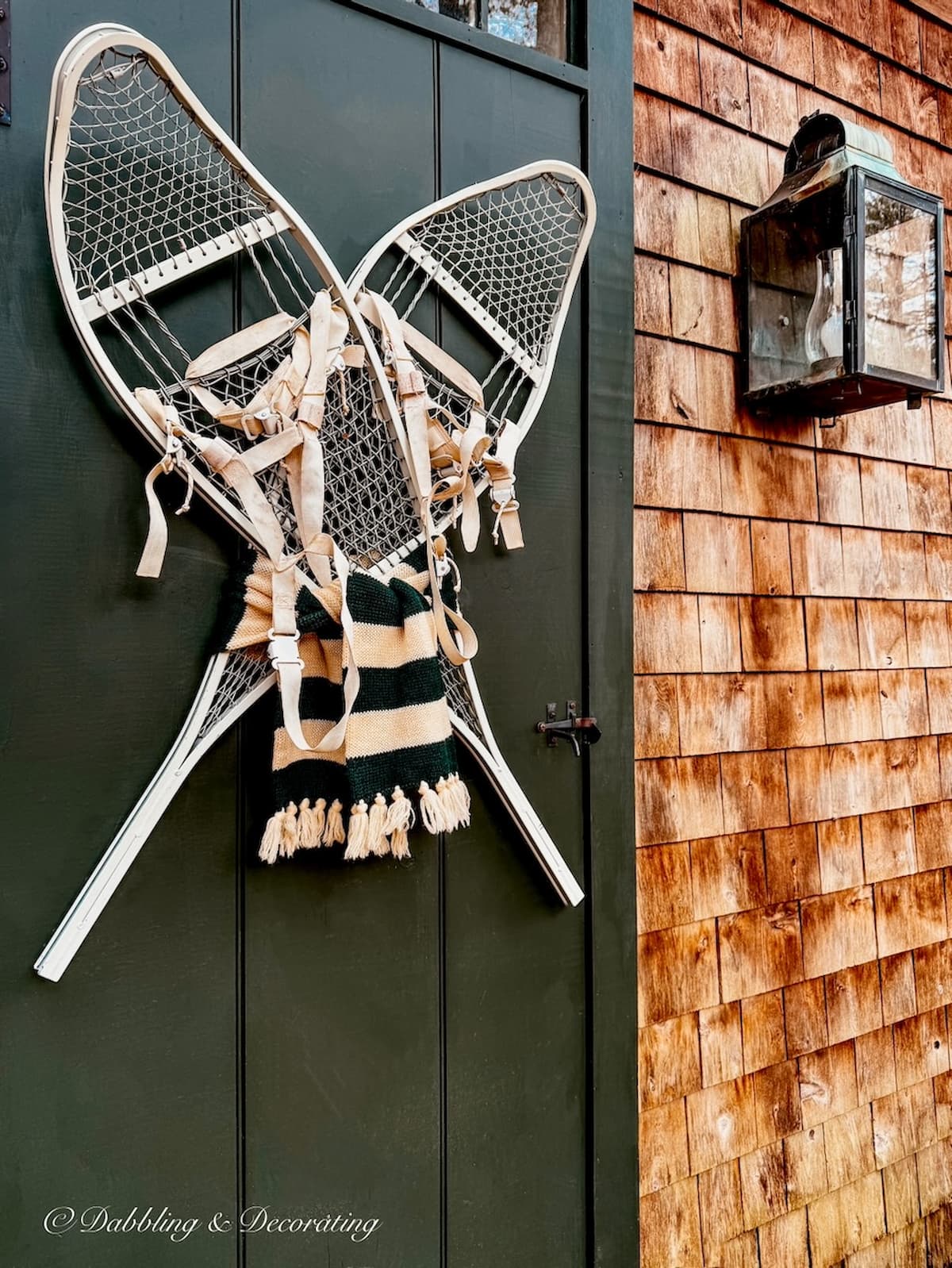 Vintage white snow shoes criss crossed on Essex Green antique front door with draped green and white scarf in winter decor ideas.