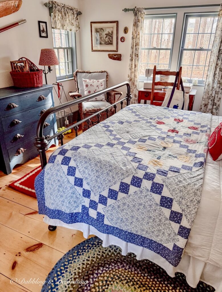 Small guest bedroom with wrought iron bed, heirloom quilted bedding, braided rug blue dresser and coastal details.