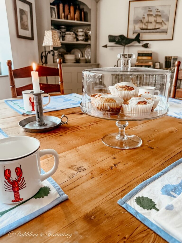 Round dining room table with glass cakes tand filled with homemade cinnamon buns for a Sunday Moment in Maine.