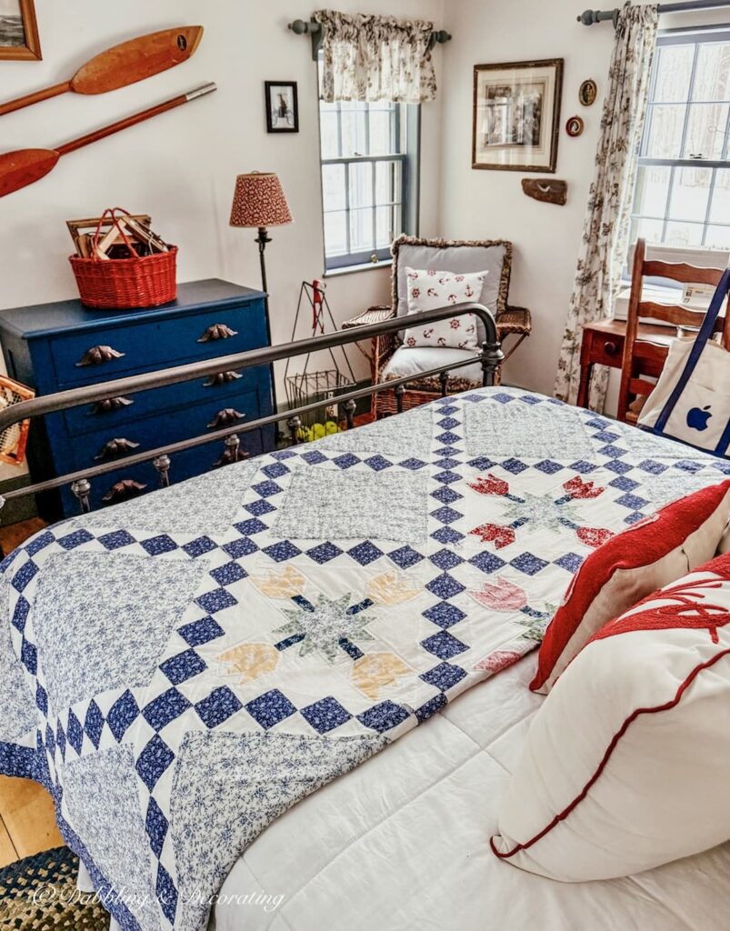 Red, white, and blue coastal vintage styled guest bedroom with quilt, navy blue dresser, wall oars and more for a Sunday Home Vibe.