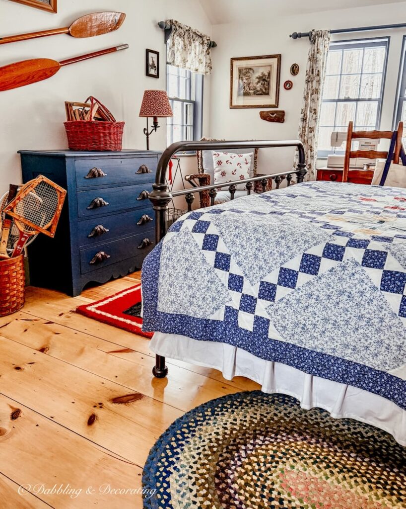 Red, white, and blue coastal vintage styled guest bedroom with quilt, navy blue dresser, wall oars and more for a Sunday Home Vibe.