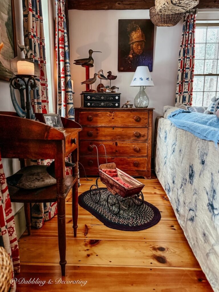 Antique styled living room with wood floors, dresser, side table and moody lighting on a snow day in Maine with a Sunday home decor vibe.