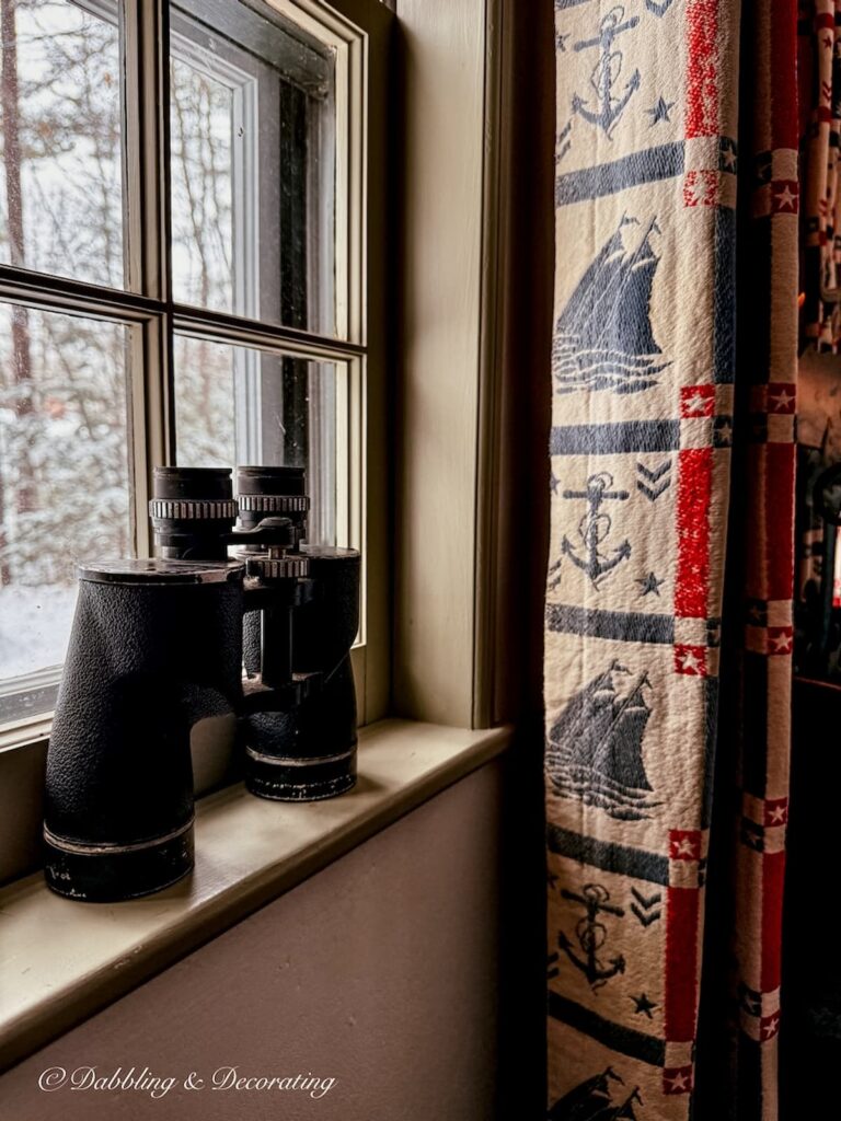 Vintage binoculars resting on moody windowsill during a snow day at home.