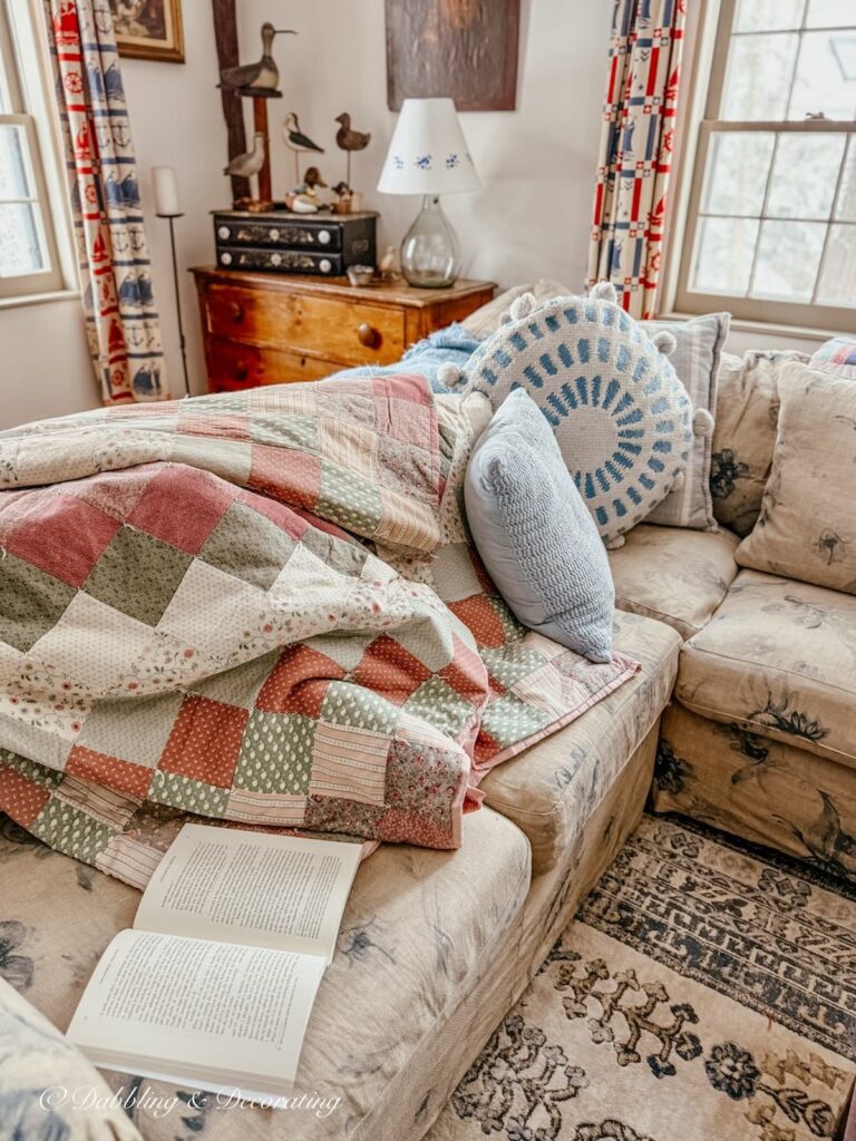 Cozy living room with handmade quilt on section and a book for a sunday home vibe in an antique decorated home.