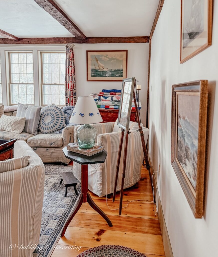 Coastal paintings on living room wall with antiques and a coastal theme.