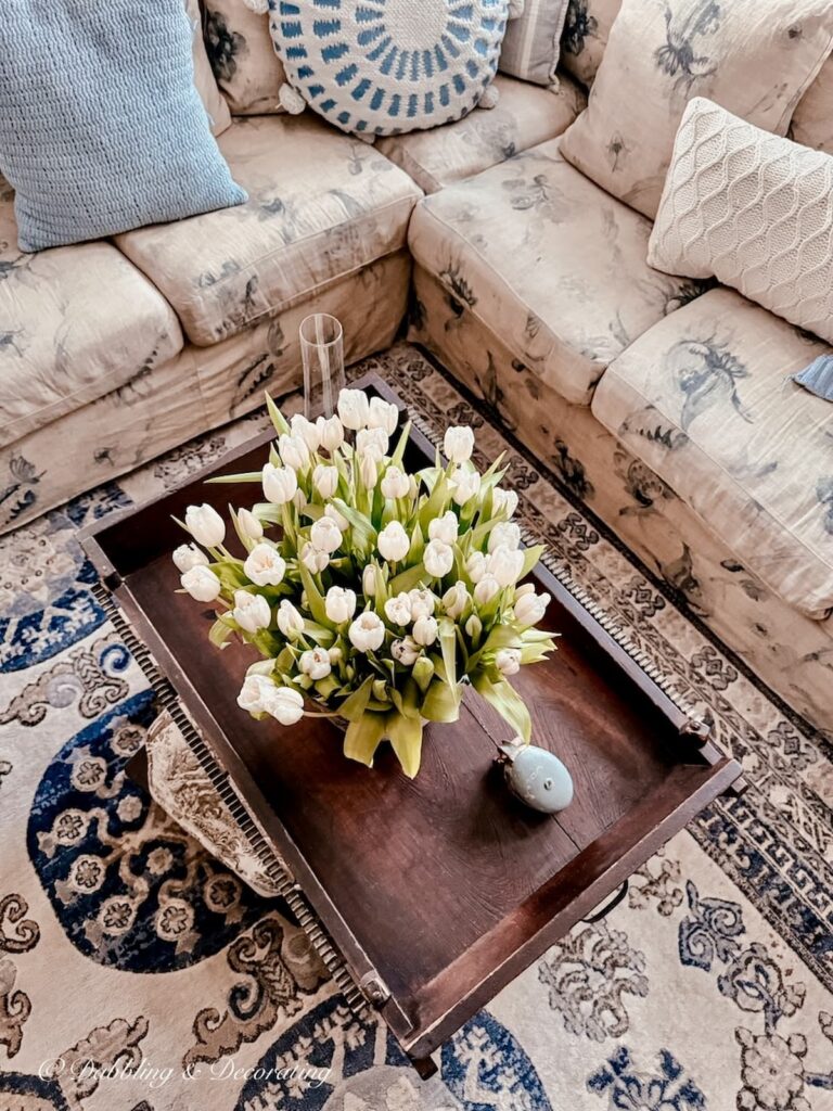 Bouquet of white tulips on antique coffee table in center of living room for a cozy Sunday home vibe.