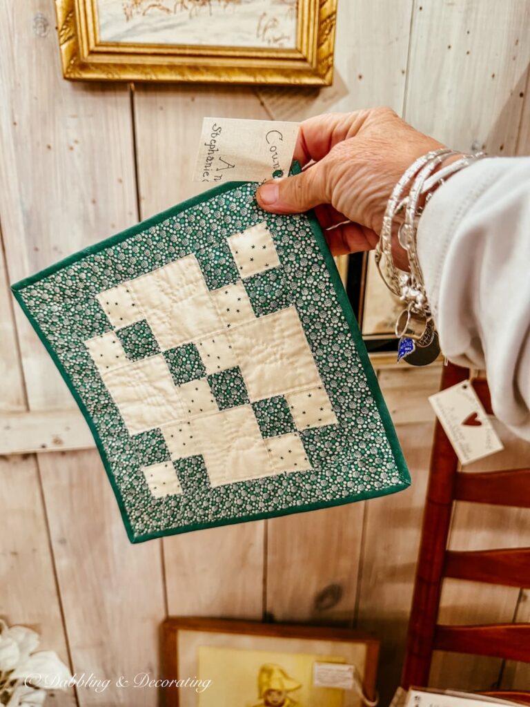 Green and white patchwork pot holder in hand at Antique store for St. Patrick's Day Decor ideas in the kitchen.