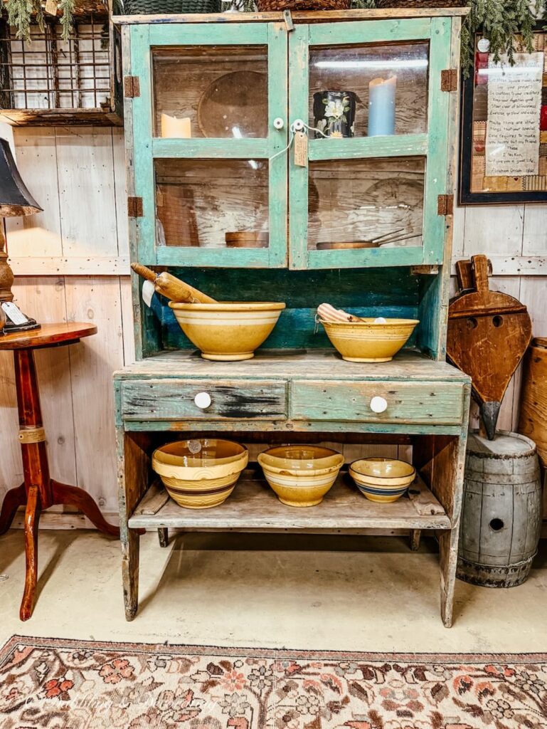 Green cabinet in antique store decorated with yellow ware for St. Patrick's Day decor ideas.