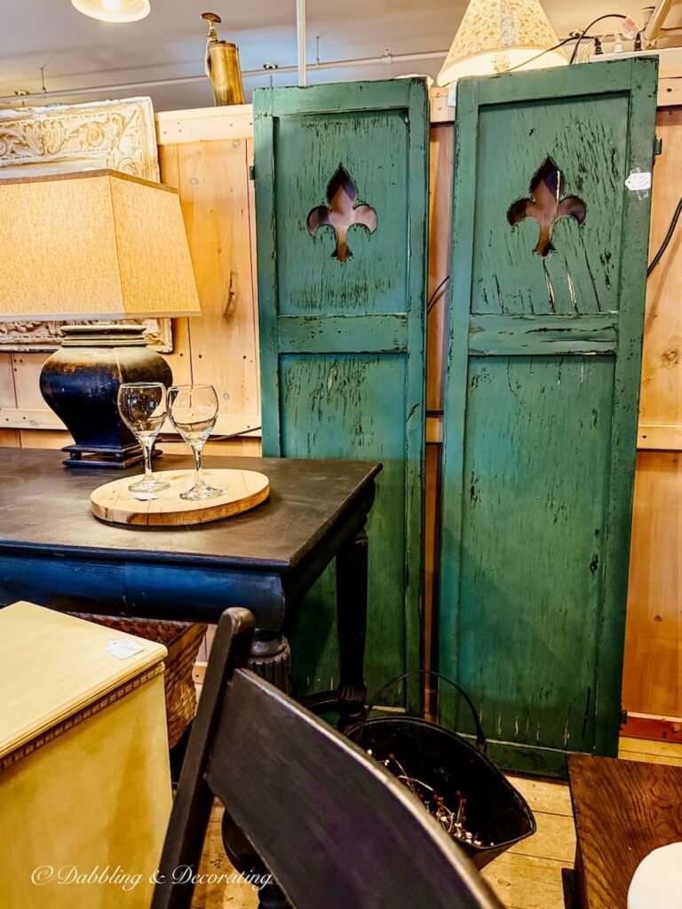 A pair of chippy green shutters in an antique store with clovers carved in for St. Patrick's day decor ideas in antique stores.