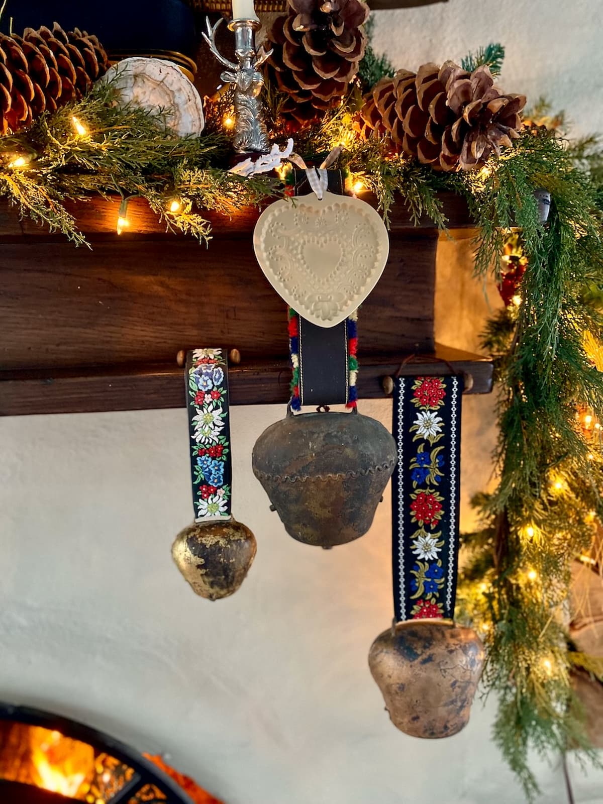 Swiss cowbells hanging from fireplace mantel in apres ski decor.
