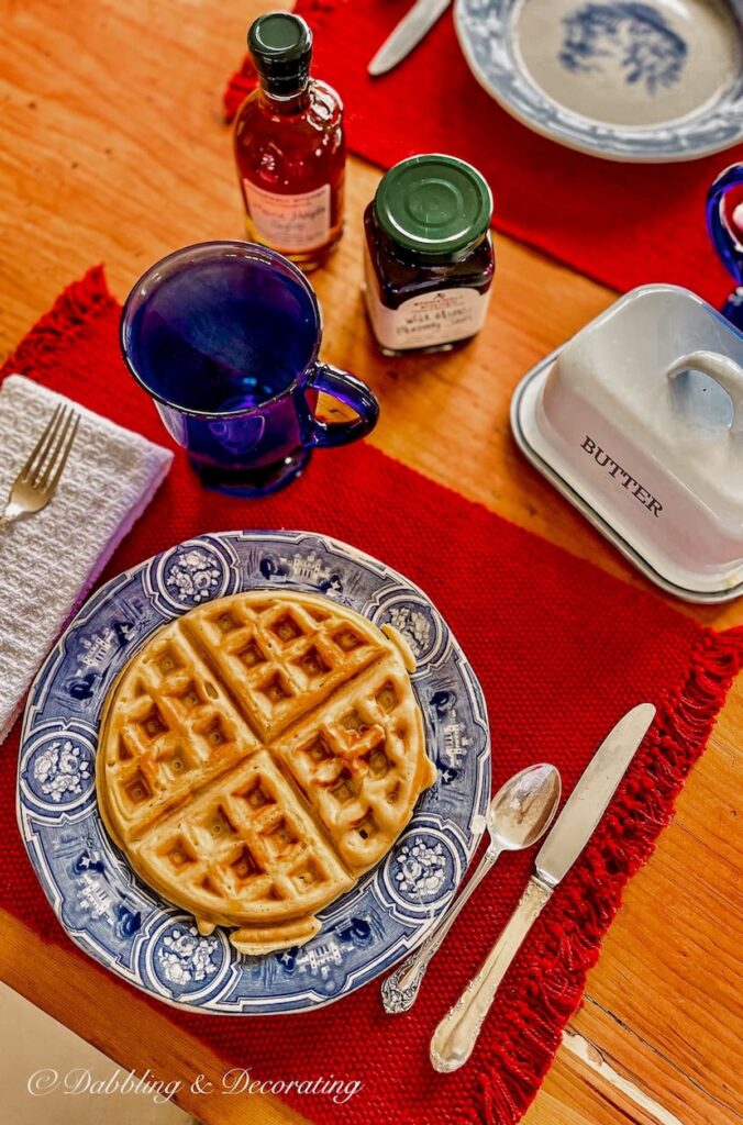 Breakfast table with waffles on vintage blue and white plate on red tablecloth with Stonewall Kitchen for a Sunday Home Trend Breakfast.