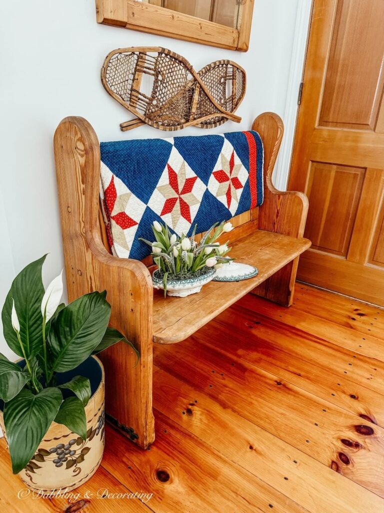 Vintage inspired entryway with vintage church pew and a draped quilt with a thrifted soup tureen planter ideas.