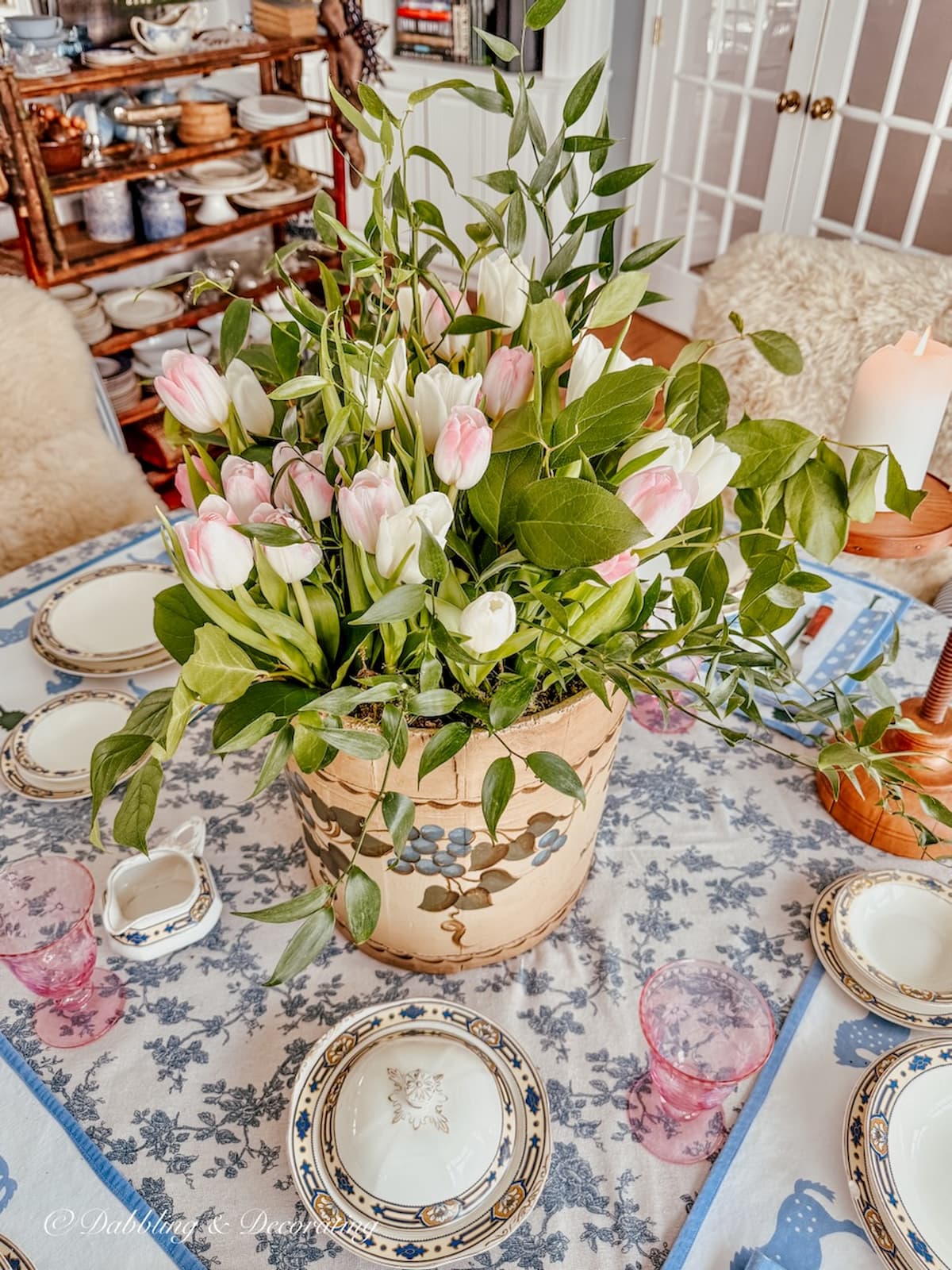 Vintage wooden maple sap bucket with spring flower bouquet on center of table in vintage styled home dining room.