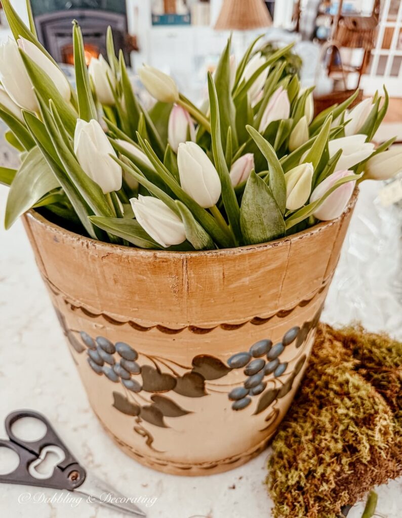 Vintage wooden flower arrangement with white tulips on counter.