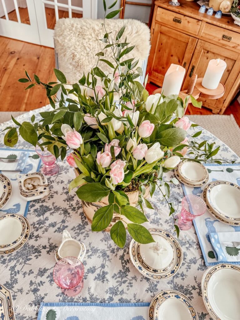 White and pink tulip table centerpiece in old wooden bucket in dining room.