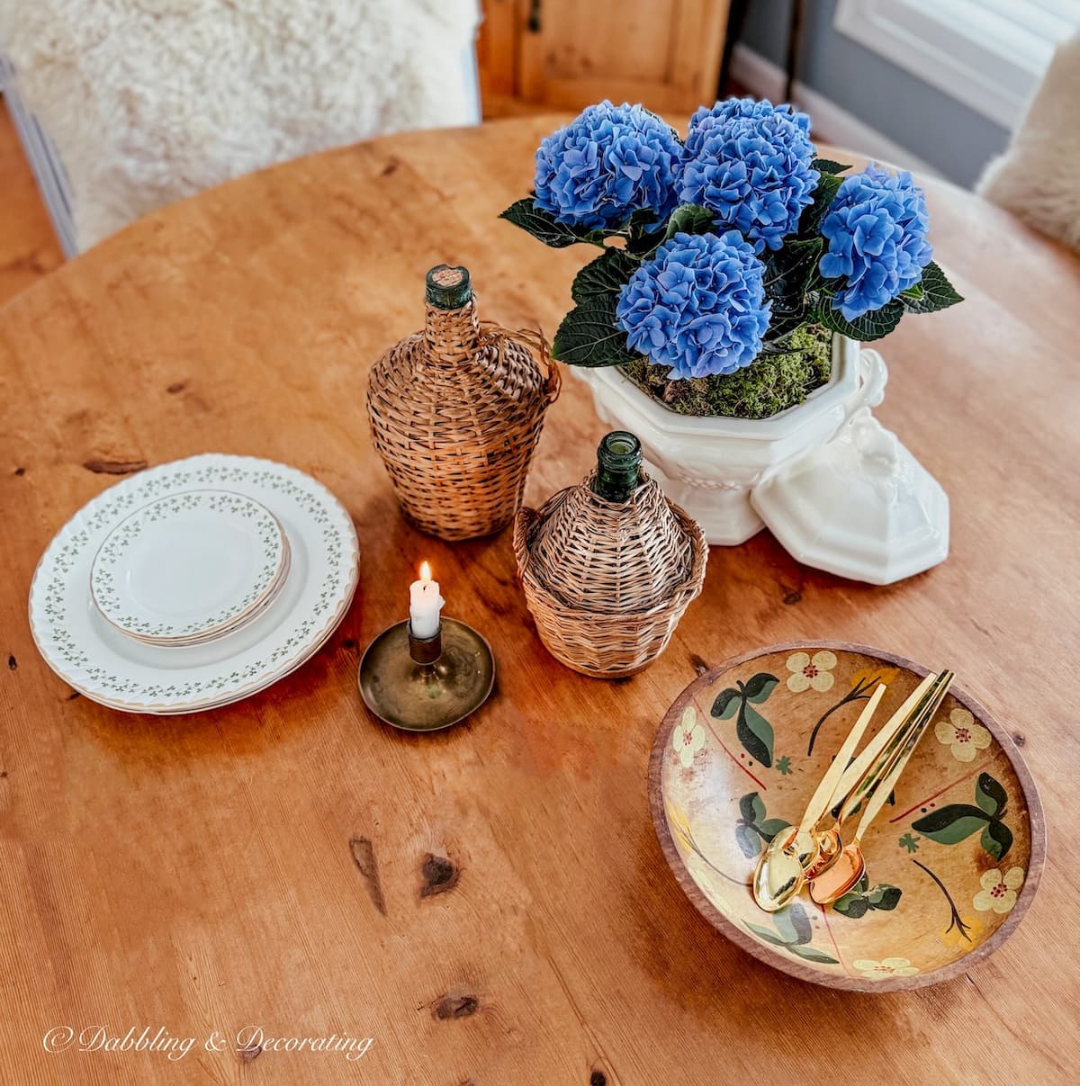 Vintage soup tureen with blue hydrangeas, vintage wooden bowl, demijohns candle and Irish dishes vintage small decor ideas on antique pine table.