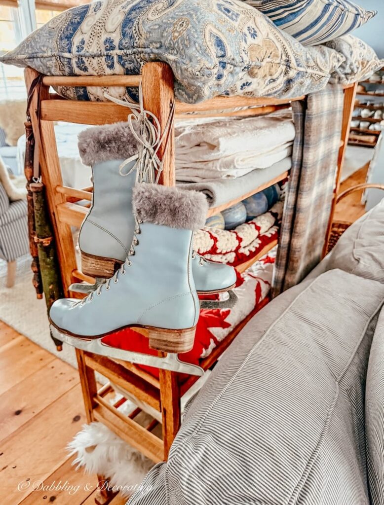A pair of blue vintage ice skates with fur gently hanging from an old cobbler rack as a room divider for small vintage decor ideas for a cozy home.