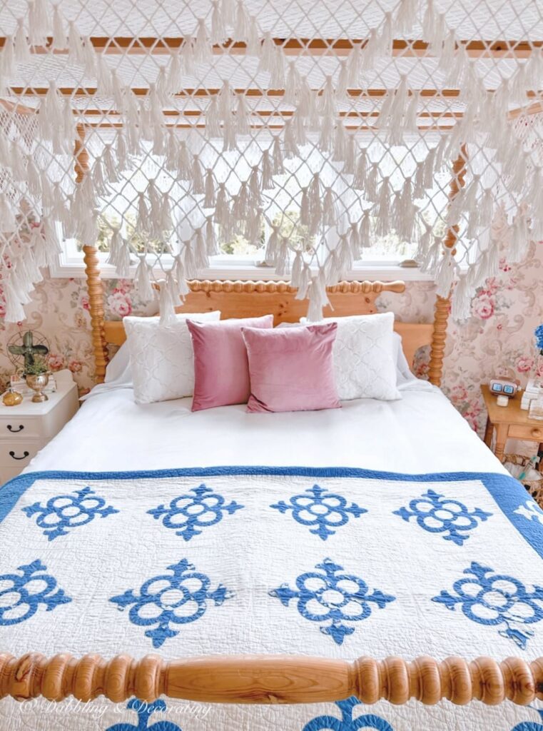 Bedroom wallpaper ideas with a canopy bed, blue and white bedding, laced canopy and pink wallpaper style.