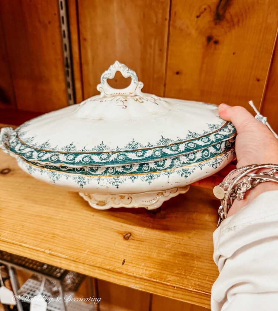 Green and white vintage soup tureen on shelf in antique store for small vintage decor ideas.