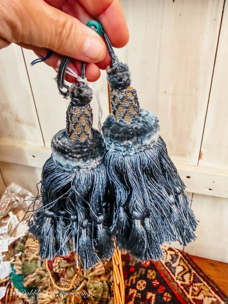 A pair of blue tassels in hand at an antique store for small vintage decor ideas.