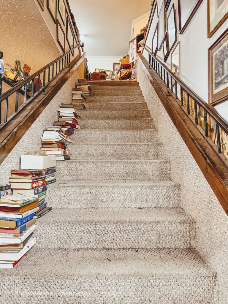 Stairs leading to the second floor at Eagle Bridge Antique Center with stacks of books.