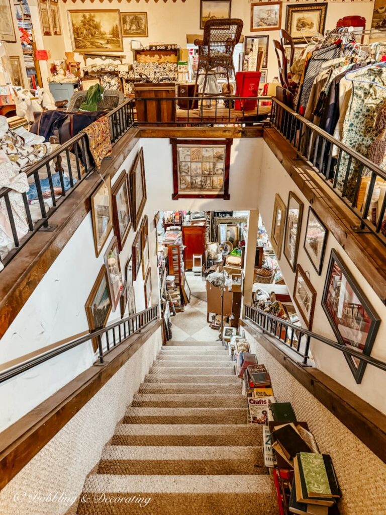 Stairs looking down from the second floor of Eagle Bridge Antique Center with floors and walls filled with vintage treasures.