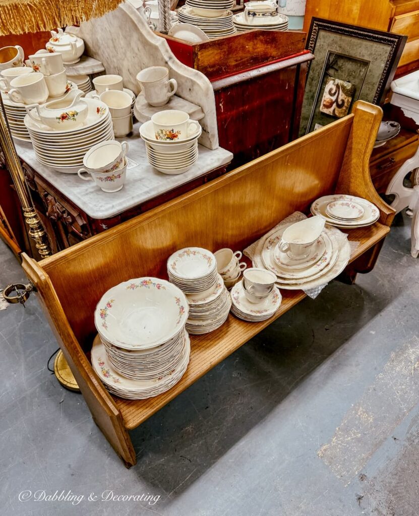 vintage church pew filled with antique dishes inside Eagle Bridge Antiques in NY.