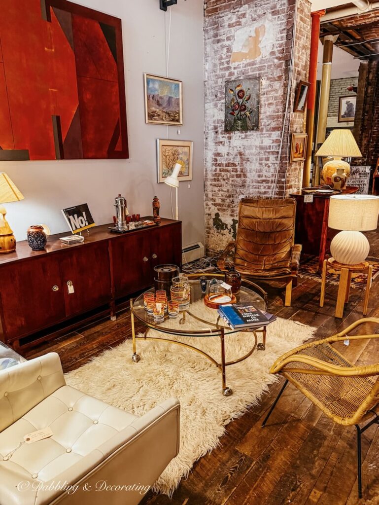 Mid century modern decor styled booth at Open House in Portland, Maine with paintings, glass tables, sheepskins and vintage barware.