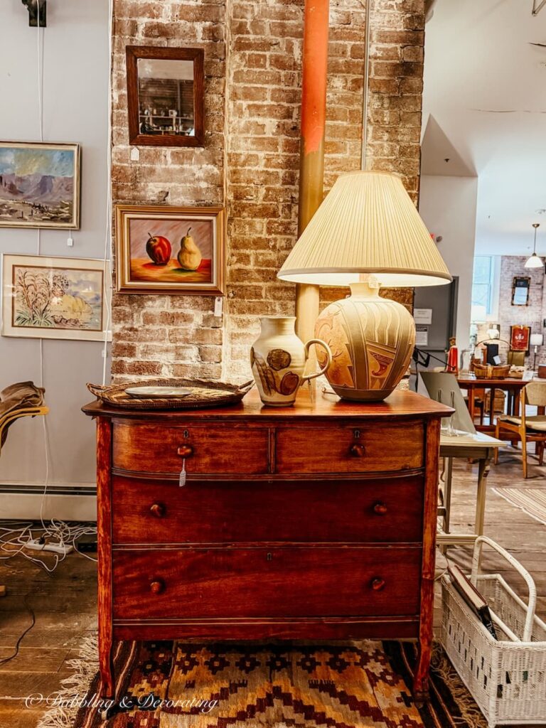 Antique dresser with lamp against brick wall inside Open House Portland, Maine eclectic vintage store.