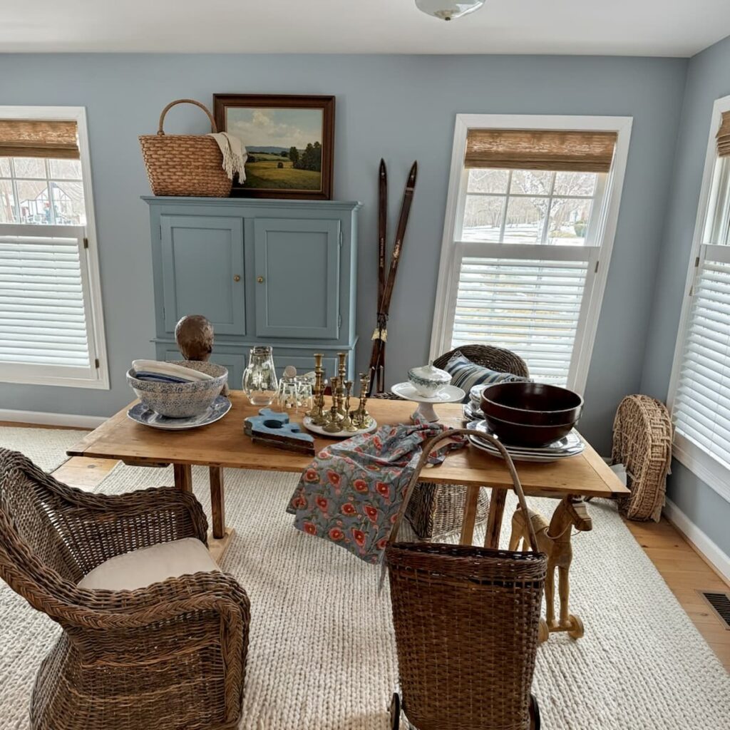 Open floor plan with Scullery-Inspired Kitchen Workroom with blue hutch and table with wicker chairs and white rug.
