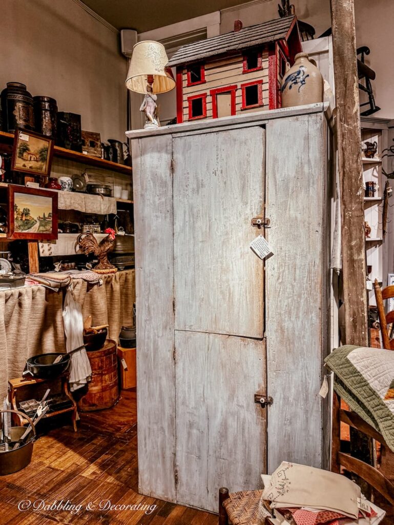 Primitive light blue hutch or cabinet standing tall in antique store.
