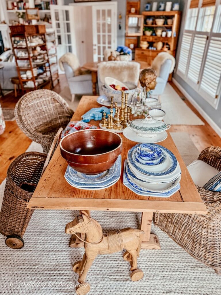 Open floor plan corner of room off kitchen with no purpose and vintage collections scattered on large pine table.