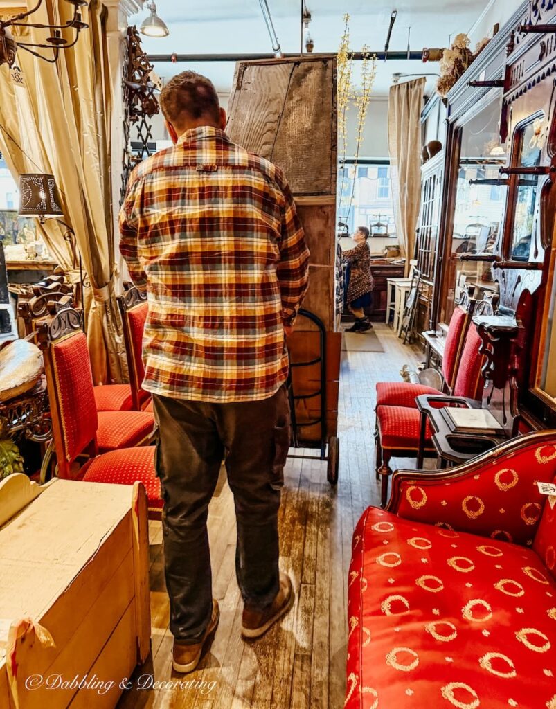 Man rolling out a large antique hutch out of Windham Antique Center in Bellows Falls, Vermont.