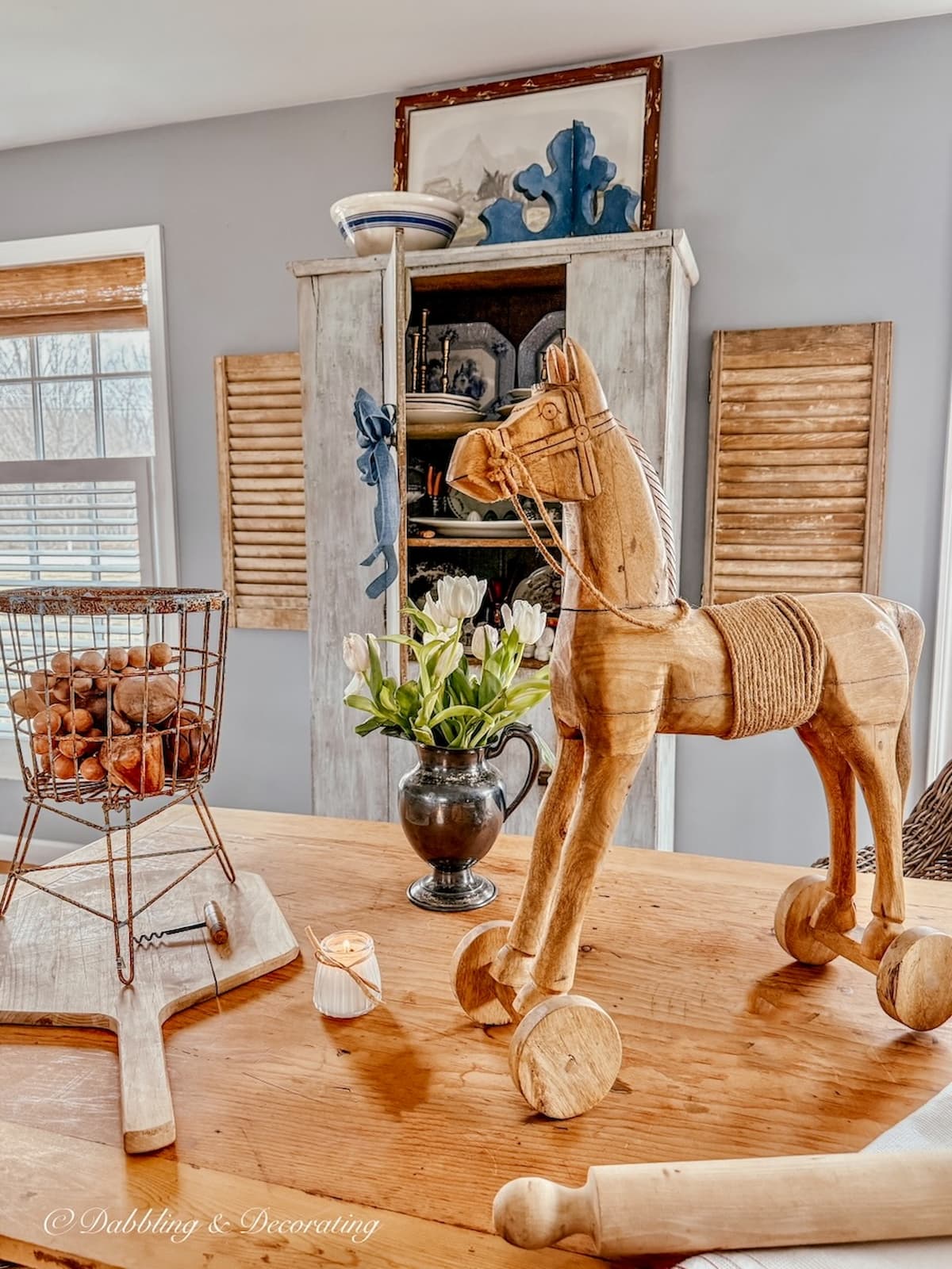 Scullery-inspired open floor plan room with vintage pine table and vintage finds with antique cupboard door open on wall.