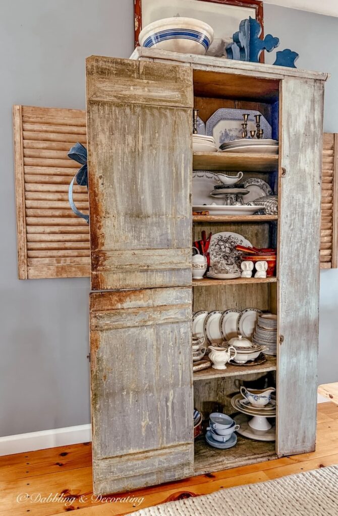 Antique cupboard ideas in a blue primitive hutch filled with vintage collections in open floor plan.