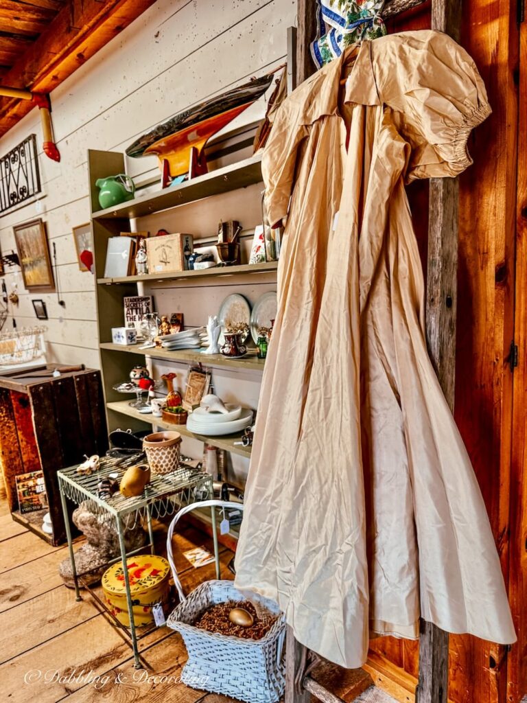 A petite antique taffeta gown in beige hanging up in a thrift store in Maine.