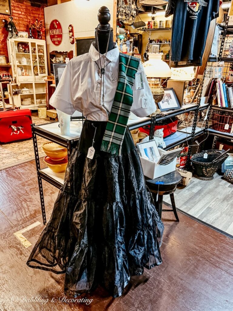 Mannequin with long black skirt, white blouse and Scottish plaid scarf antiquing in Maryland.