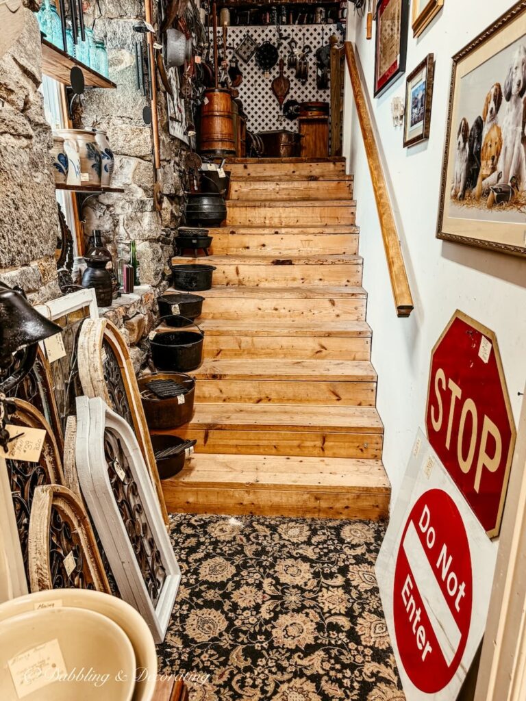 Inside the Seneca Cannery antiquing in Maryland; wood steps going upstairs with wrought iron pots and stop signs and mirrors.