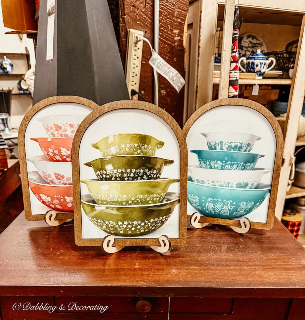 Framed pictures of stacks of colored Pyrex on table in antique store antiquing in Maryland.